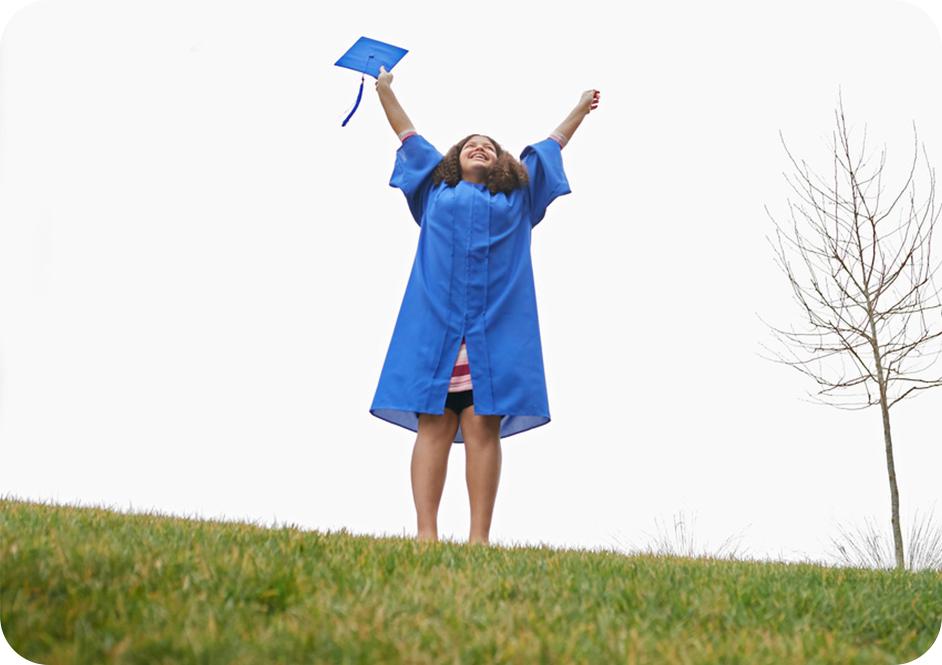 Girl wearing blue graduation robe jumping in the air while throwing blue graduation cap in the air