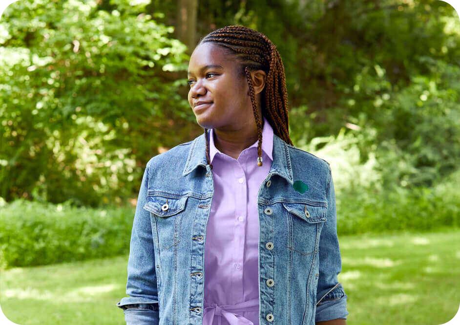 Girl wearing denim Girl Scout jacker and light purple button down shirt