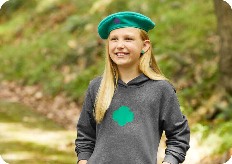 Girl wearing dark grey Girl Scouts hooded sweatshirt and green beret hat