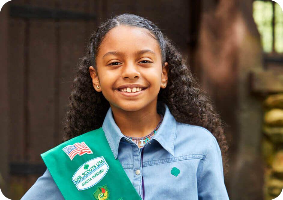 Girl smiling and wearing green Girl Scout sash